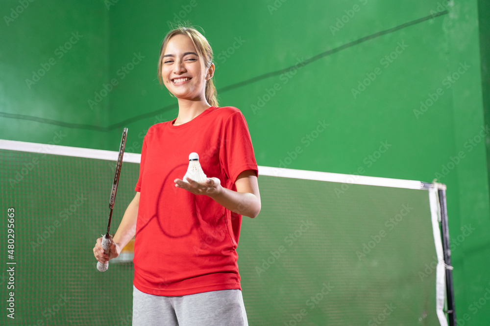 Smiling female badminton player holding racket and shuttlecock