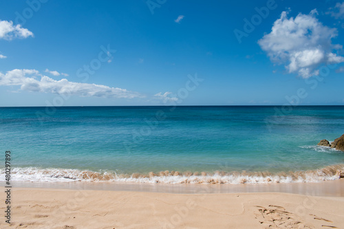 A view from the sand of a beach on the island of Barbados in the Caribbean with clean  blue water. Image is great for postcards.