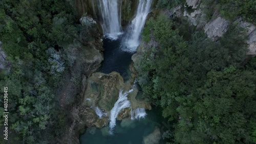 Drone video of a crane plane of ascent and rear cenital over the Manojlovac waterfall on the Krka river in Croatia ending with the horizon on the mountain. photo