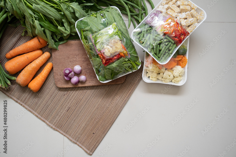 Using plastic food wrappers to wrap and store vegetables Stock Photo