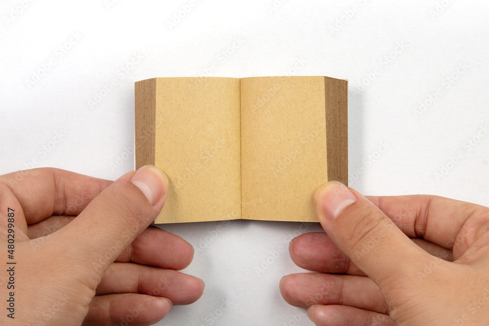 Hand holding a small book with blank pages isolated on white background Hand holding a small book with blank pages isolated on white background