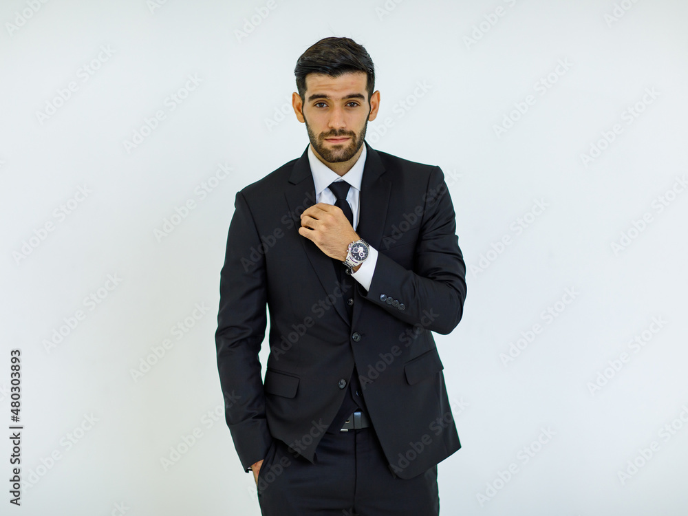 Portrait studio cut out shot of Caucasian success handsome bearded male businessman in formal black suit and necktie standing smiling look at camera holding hands in pants pockets on white background Portrait studio cut out shot of Caucasian success handsome bearded male businessman in formal black suit and necktie standing smiling look at camera holding hands in pants pockets on white background