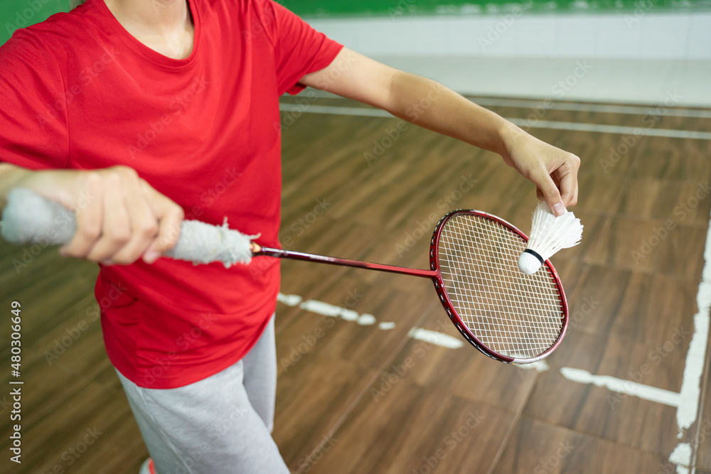 Female badminton player's holding racket and shuttlecock in service position