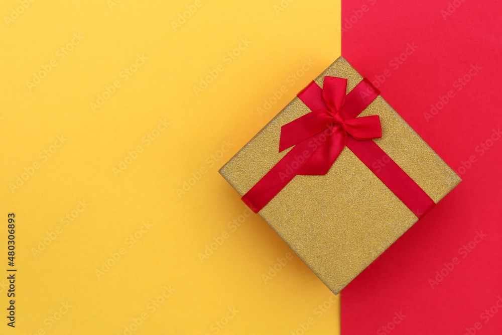 The gift box stands at the same time on the border of two colors, yellow and red. The gift box stands at the same time on the border of two colors, yellow and red.