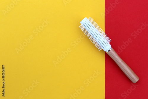 A white hair styling brush lies on a bright background.