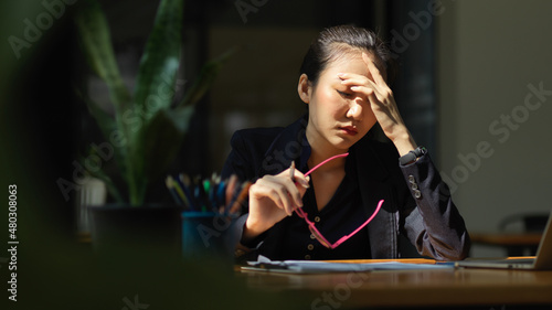 A businesswoman has a headache or eye-strain after having overworked.