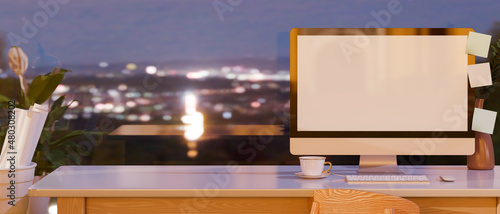 Office workspace with desktop computer mockup over evening view in the background. © bongkarn