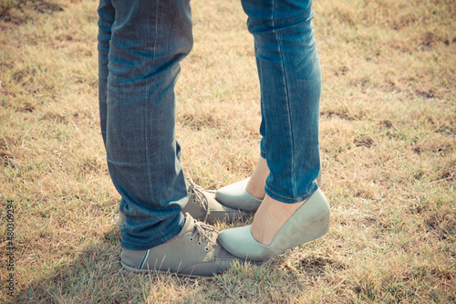 couple standing like kissing in a park, woman foot standing and tiptoe on man
