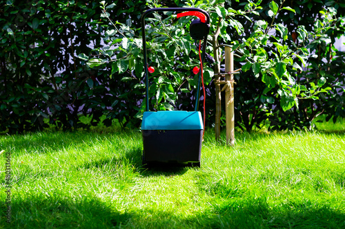Fotografija Back view on an electric lawn mower mowing down the long grass in a garden or ba