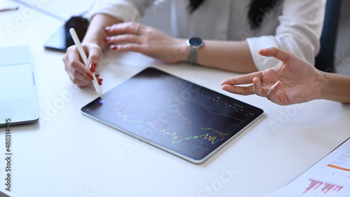 Cropped shot two businesspeople analyzing investment data in digital tablet together.