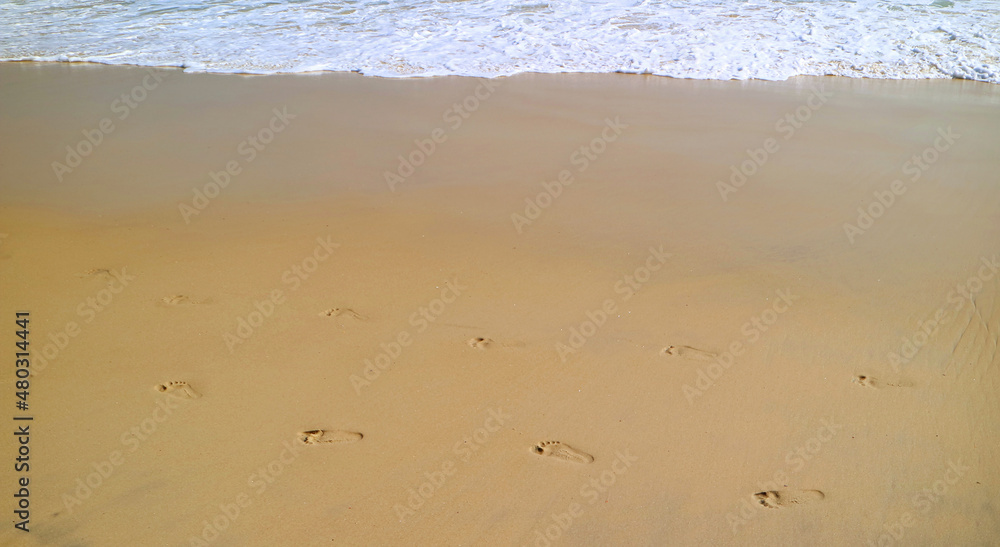 Footprints of two person on the beach with sea foam splashing Footprints of two person on the beach with sea foam splashing