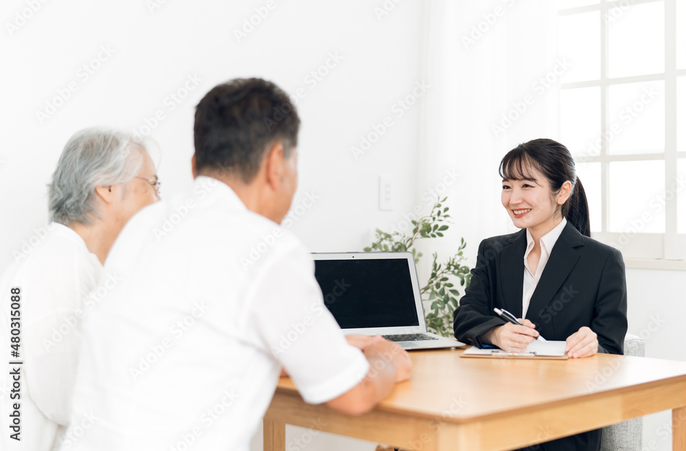 資料で説明するスーツ姿の女性と高齢者夫婦
資料で説明するスーツ姿の女性と高齢者夫婦