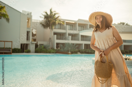 Young Asian woman relaxing beside the pool at luxury hotel. travel and summer concept background. 