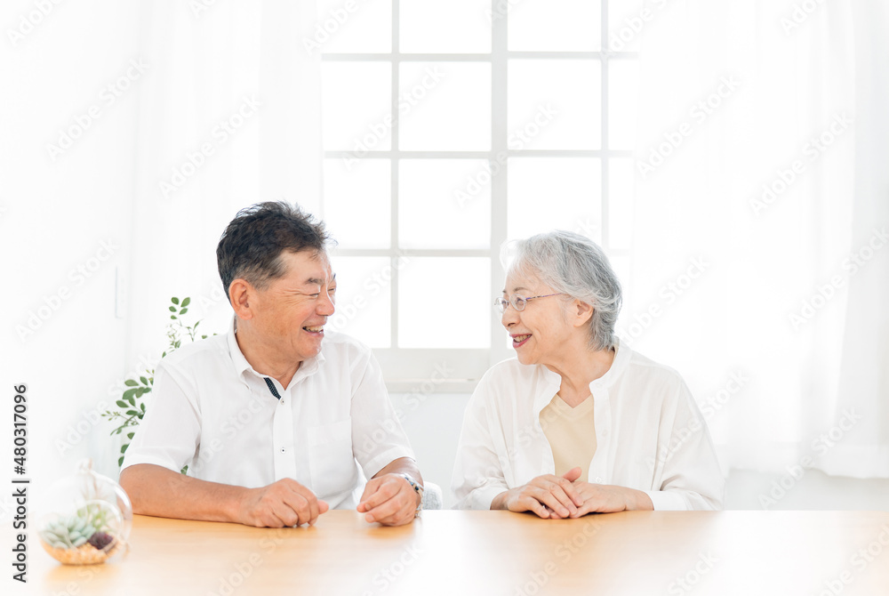 テーブルに座る高齢者夫婦（話す）
