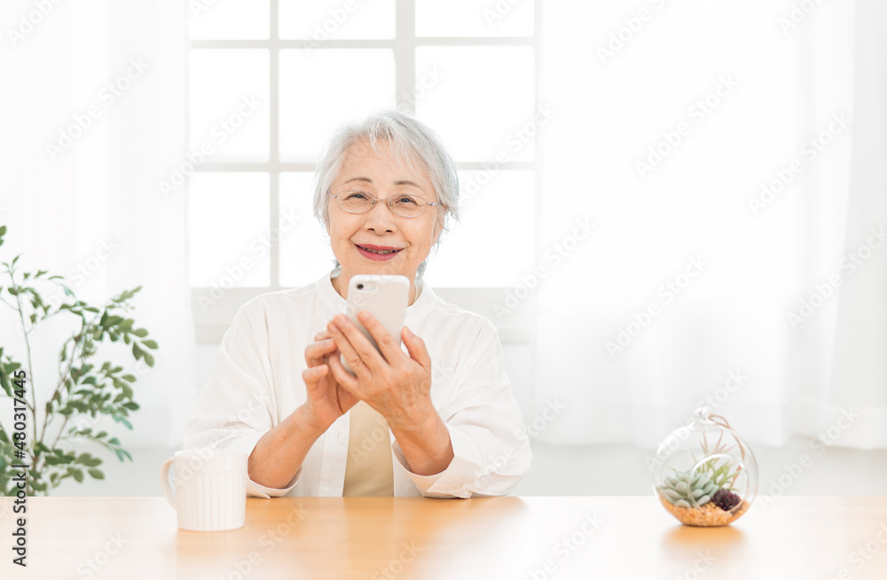 スマホを使う高齢者女性（笑顔）
