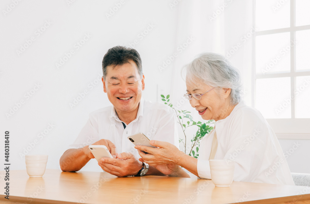スマホを使う高齢者夫婦（笑顔）
