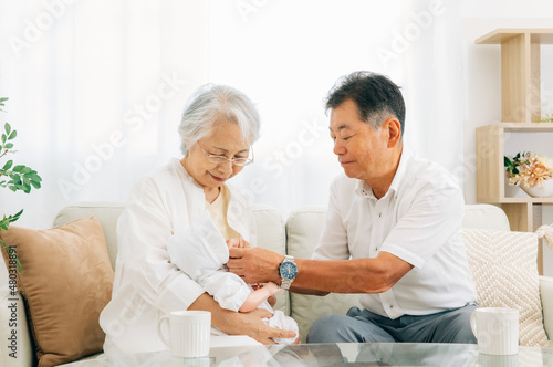 孫を抱く高齢者女性と男性  © buritora