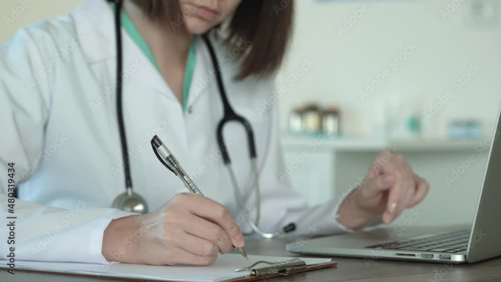 Close up view of male doctor using laptop and taking notes in notepad . Woman doctor in white coat working close-up side view. Distance consultation. Social media concept. Faceless. 4k footage Close up view of male doctor using laptop and taking notes in notepad . Woman doctor in white coat working close-up side view. Distance consultation. Social media concept. Faceless. 4k footage