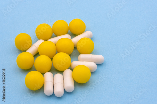 Medicines in capsules and dragees on blue background. Copy space.