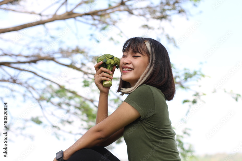 Smiling young woman holding broccoli healthy food Smiling young woman holding broccoli healthy food