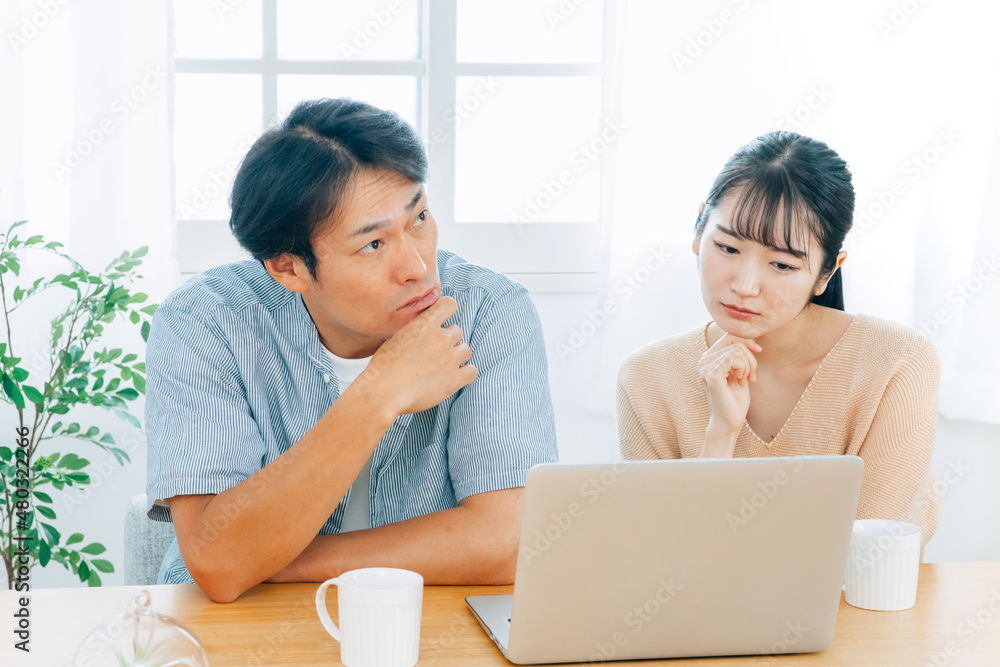 ノートパソコンを見る夫婦（困る）
