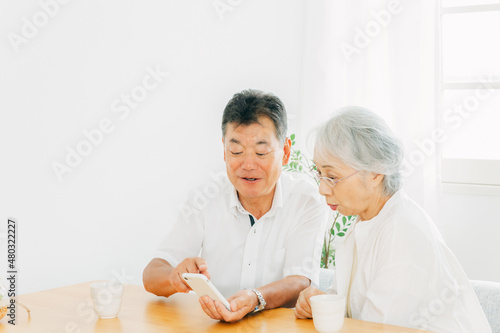 スマホを使う高齢者夫婦（笑顔） 