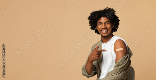 Covid-19 Vaccination. Smiling millennial african american guy pointing at plaster on arm