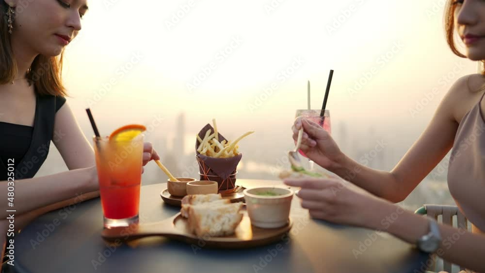 4K Beautiful Asian woman friends meeting and dinner party together at skyscraper rooftop restaurant in metropolis at summer sunset. Female friend enjoy outdoor lifestyle activity in the city at night 4K Beautiful Asian woman friends meeting and dinner party together at skyscraper rooftop restaurant in metropolis at summer sunset. Female friend enjoy outdoor lifestyle activity in the city at night