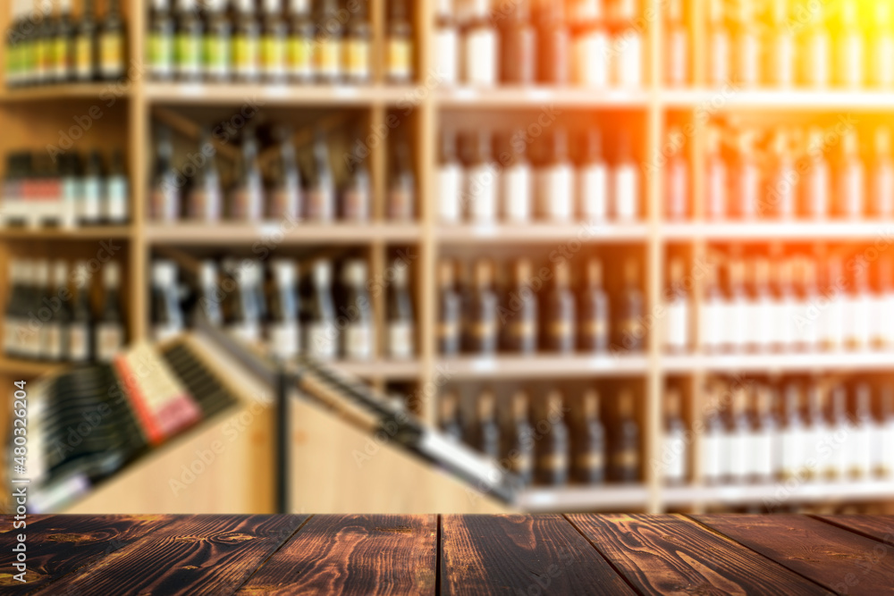 Wine wooden table background. Blurred wine shop with bottles on the counter.