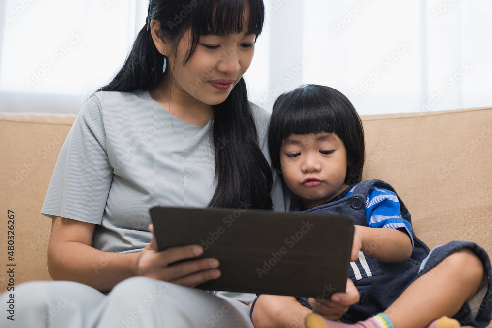Happy asian family mother and son using tablet for education. Little boy watching funny social media. Mom with kid using tablet video call to father. Happy asian family mother and son using tablet for education. Little boy watching funny social media. Mom with kid using tablet video call to father.