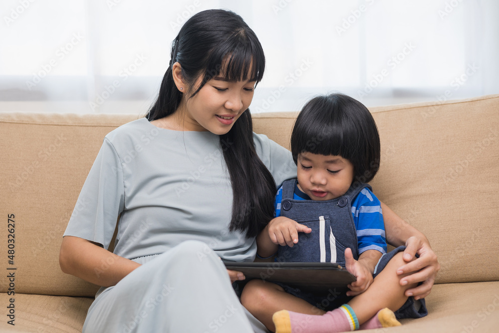 Happy asian family mother and son using tablet for education. Little boy watching funny social media. Mom with kid using tablet video call to father. Happy asian family mother and son using tablet for education. Little boy watching funny social media. Mom with kid using tablet video call to father.
