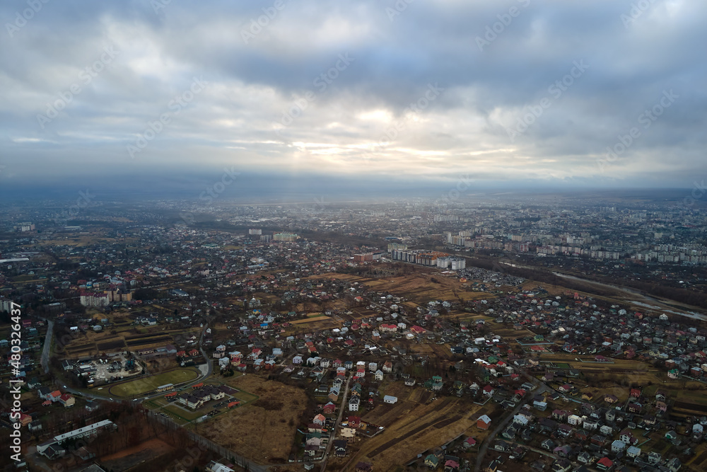 Aerial view of rural homes and distant high rise apartment buildings in city residential area during cloudy weather