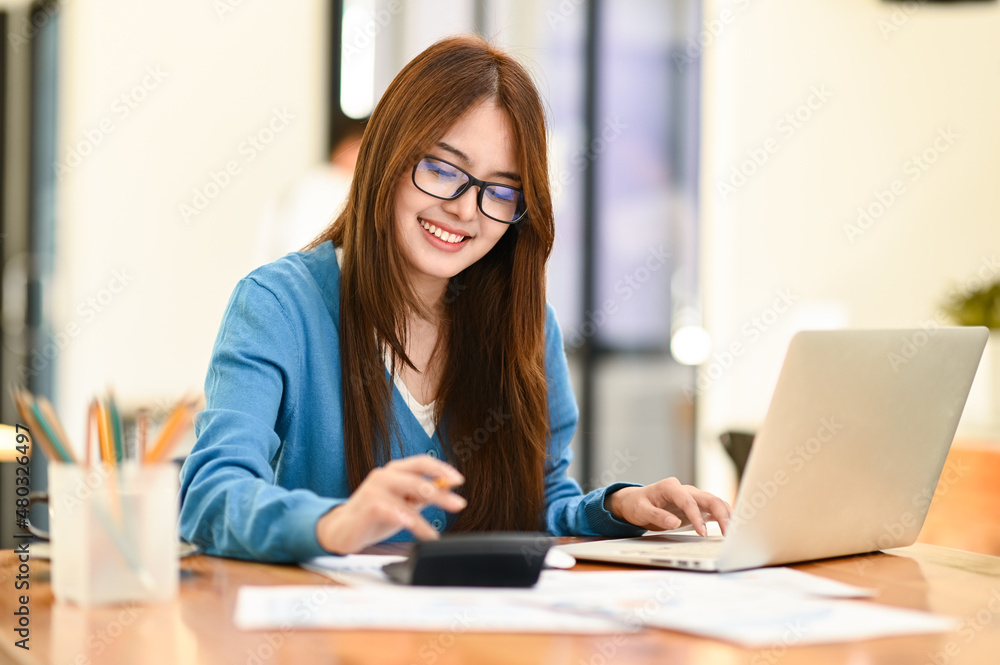 A beautiful woman working with laptop and calculator.