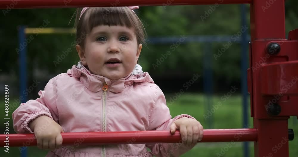 Cute baby girl having fun climbing monkey bars at park Cute baby girl having fun climbing monkey bars at park