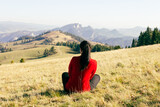 A young girl sits on the ground and looks at the beautiful landscape of autumn mountains