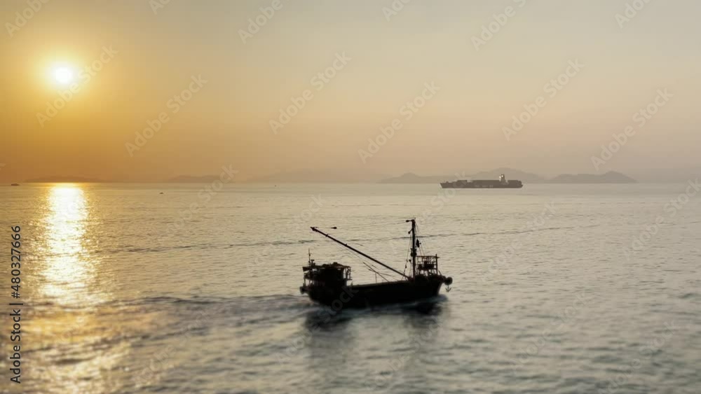 Static shot of Fishing Boat Crossing from left to right as the Sun sets. Cargo ship in the background, South China Sea Static shot of Fishing Boat Crossing from left to right as the Sun sets. Cargo ship in the background, South China Sea