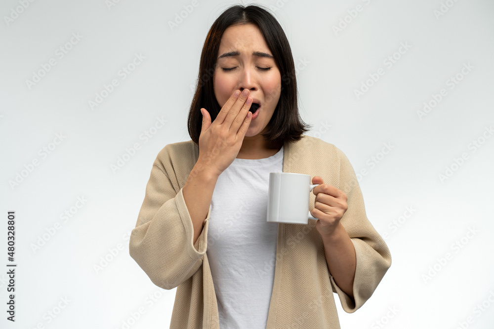 Asian woman wearing domestic clothes holding cup of coffee in hand and yawning at morning Asian woman wearing domestic clothes holding cup of coffee in hand and yawning at morning