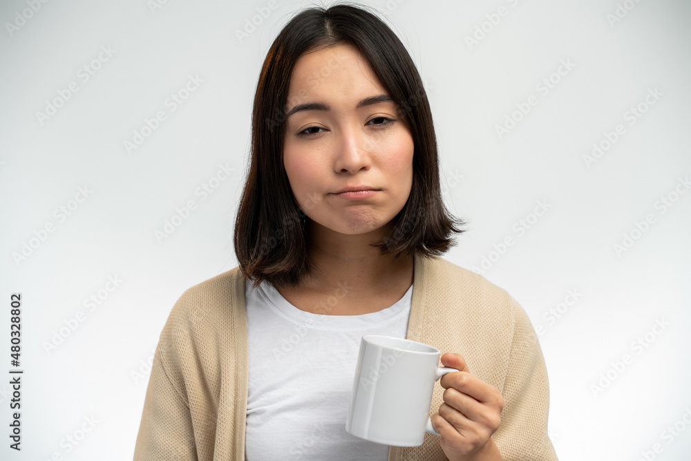 Sleepy asian ethnic female with sleepy eyes holding mug while drinking coffee Sleepy asian ethnic female with sleepy eyes holding mug while drinking coffee