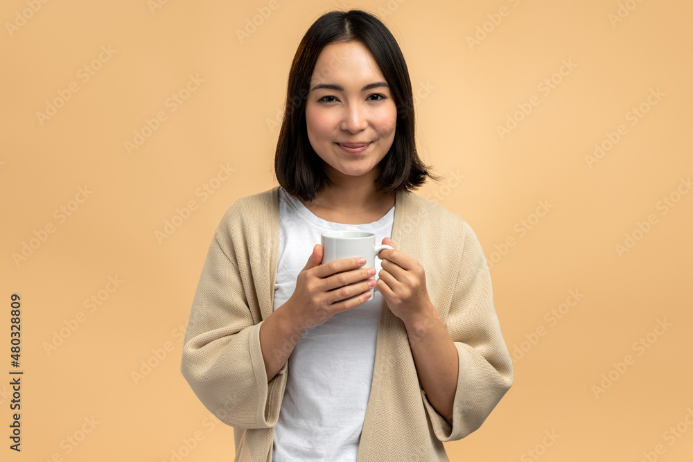 Delighted young asian ethnic woman in domestic wear smiling and looking at camera Delighted young asian ethnic woman in domestic wear smiling and looking at camera