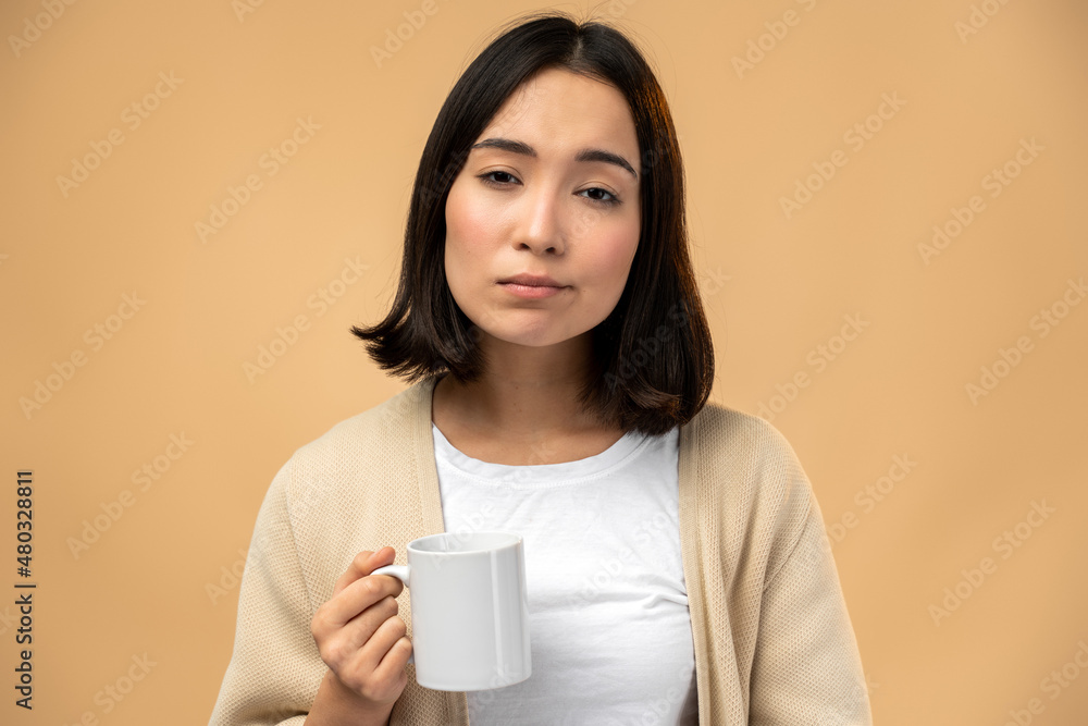 Tired sleepy woman holding cup of coffee, looking at the camera with tired expression Tired sleepy woman holding cup of coffee, looking at the camera with tired expression