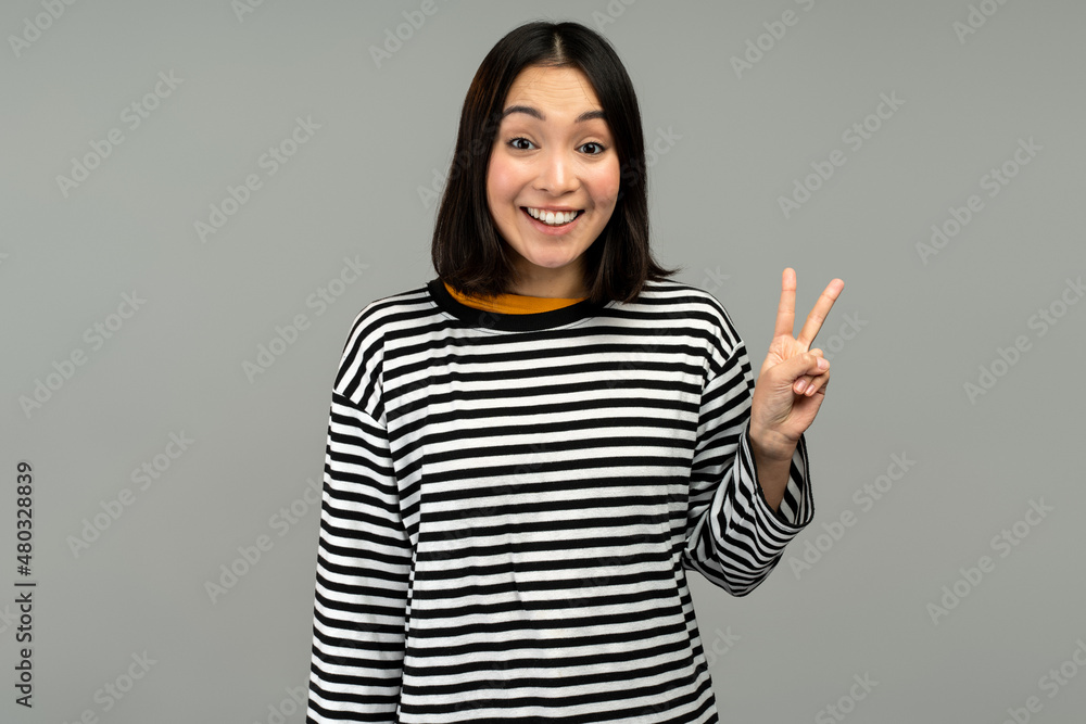 Happy friendly woman looking at camera with toothy smile, showing v sign, peace gesture Happy friendly woman looking at camera with toothy smile, showing v sign, peace gesture