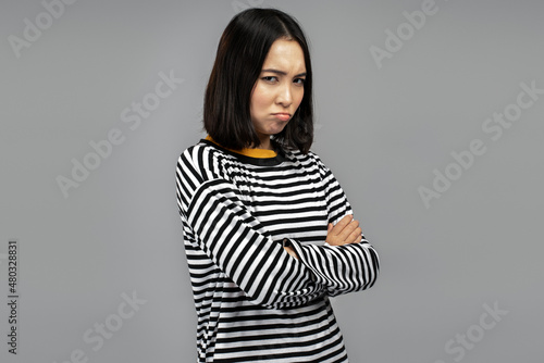 Portrait of unhappy offended woman standing with folded hands, looking at the camera © speed300