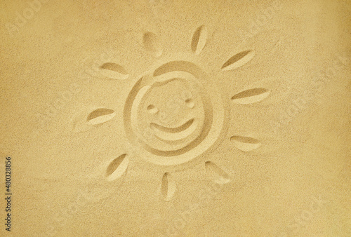 smiling sun face drawn in sand, summer beach holiday