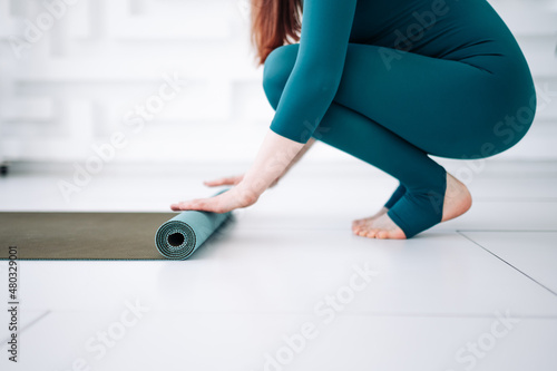 Yoga at home woman rolling pink exercise mat in living room