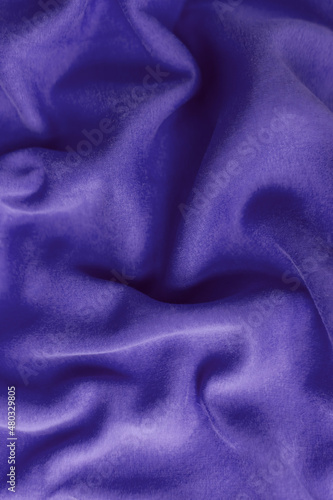 Fabric with waves colored in violet color of the year 2022. Trendy color very peri. Fabric backdrop, cloth texture, view from above.