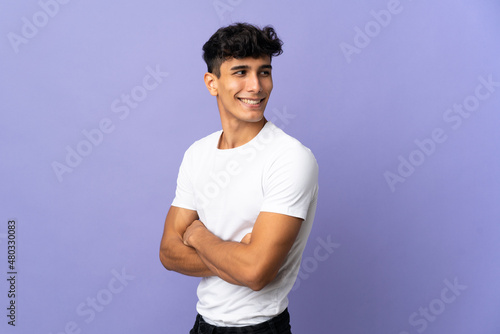 Young Argentinian man isolated on background with arms crossed and happy