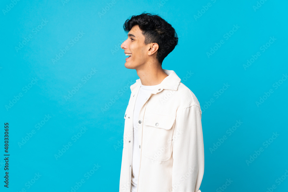Young Argentinian man isolated on background laughing in lateral position Young Argentinian man isolated on background laughing in lateral position