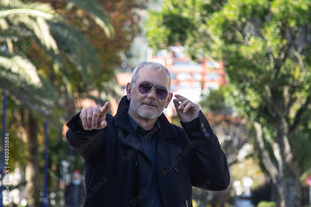 middle-aged man in coat and sunglasses walking in the park middle-aged man in coat and sunglasses walking in the park