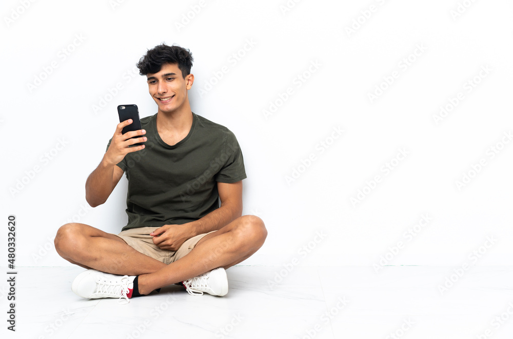 Young Argentinian man sitting on the floor making a selfie Young Argentinian man sitting on the floor making a selfie