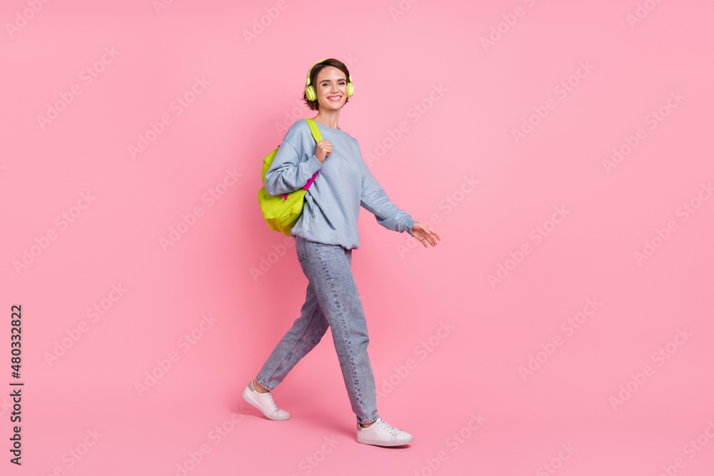 Full body photo of cute millennial lady go wear pullover jeans footwear headphones bag isolated on pink background Full body photo of cute millennial lady go wear pullover jeans footwear headphones bag isolated on pink background